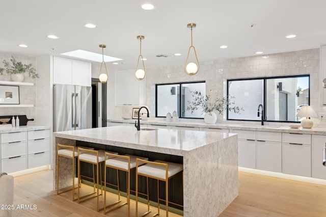 kitchen with white cabinets, light wood-type flooring, and a sink