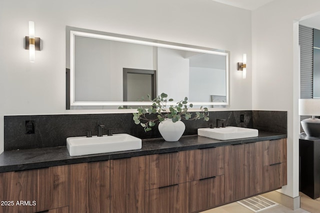 full bath featuring decorative backsplash, double vanity, visible vents, and a sink