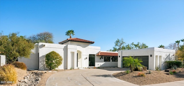 view of front of property featuring stucco siding, a tiled roof, concrete driveway, and a garage