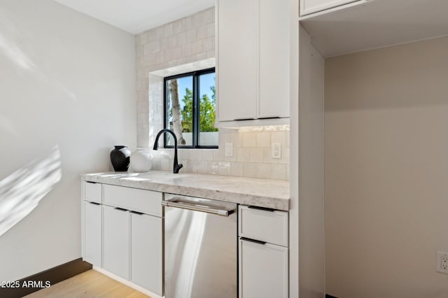 kitchen featuring a sink, white cabinets, decorative backsplash, light stone countertops, and dishwasher