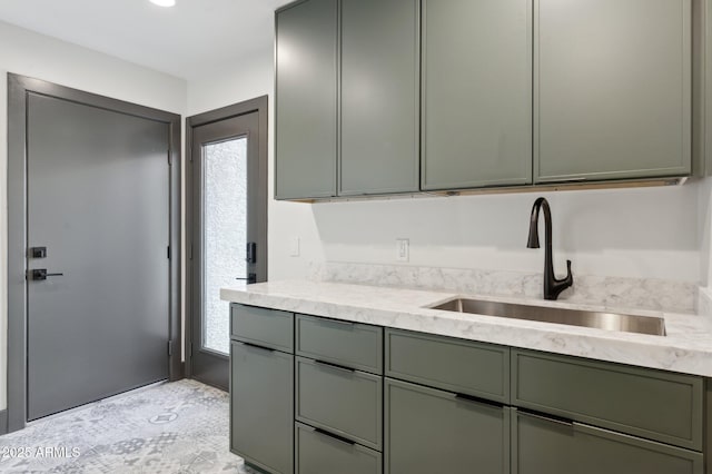kitchen with a sink, light stone countertops, and green cabinetry