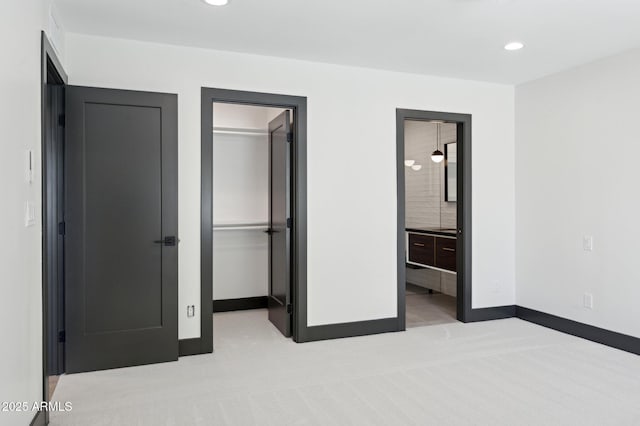 unfurnished bedroom featuring a spacious closet, recessed lighting, carpet, and baseboards
