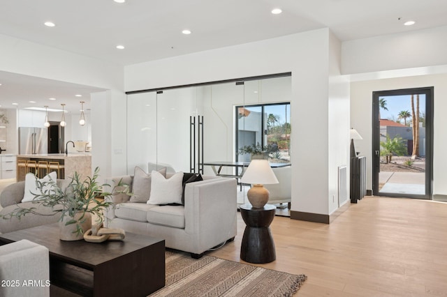living area featuring recessed lighting, light wood-type flooring, and baseboards