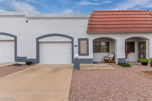 view of front of house with driveway, a tiled roof, a garage, and stucco siding