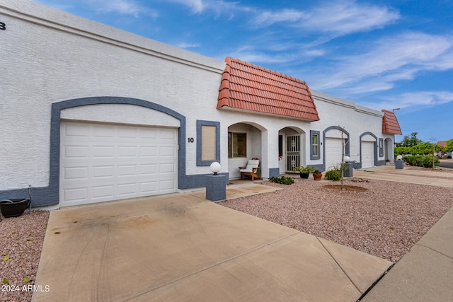 view of front of house featuring concrete driveway, a tile roof, an attached garage, and stucco siding