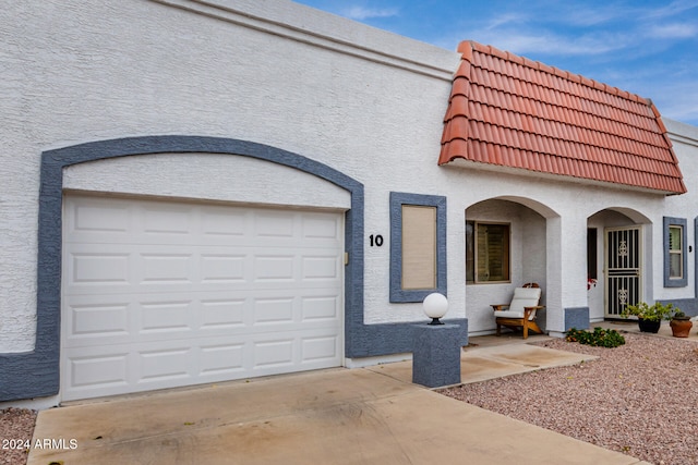 view of front facade featuring a garage, a tiled roof, concrete driveway, and stucco siding