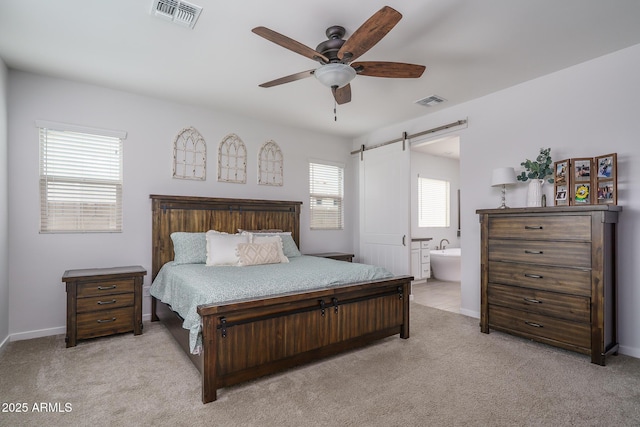 8513 N 172nd Ln, Waddell, AZ 85355 - bedroom featuring a barn door, visible vents, light colored carpet, and connected bathroom