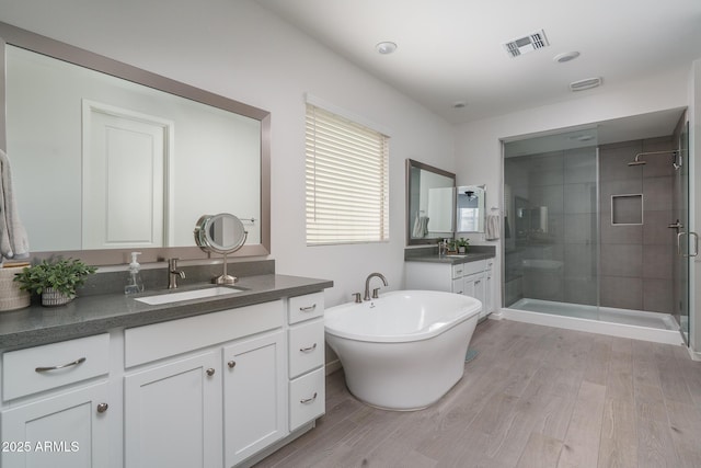 8513 N 172nd Ln, Waddell, AZ 85355 - bathroom featuring two vanities, a shower stall, visible vents, a sink, and wood finished floors