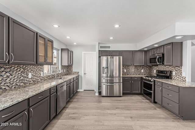 10440 E Osage Ave, Mesa, AZ 85212 - kitchen with stainless steel appliances, a sink, light stone countertops, decorative backsplash, and light wood finished floors