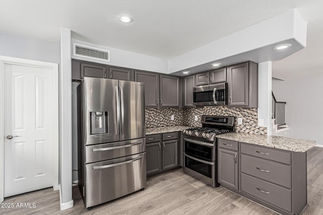 10440 E Osage Ave, Mesa, AZ 85212 - kitchen featuring appliances with stainless steel finishes, a peninsula, light wood-type flooring, light stone counters, and recessed lighting