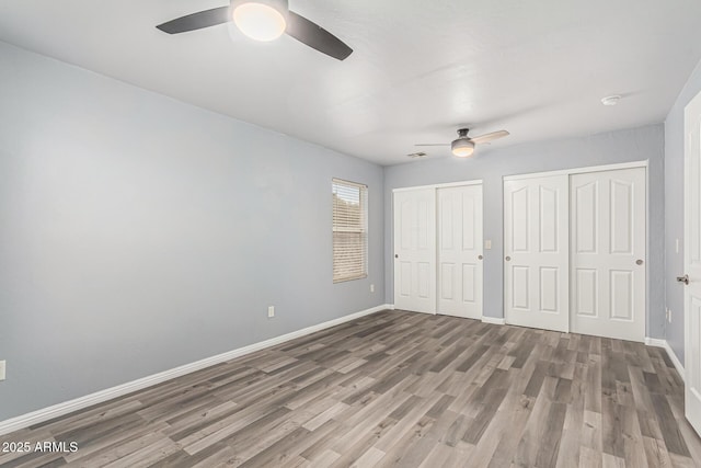 10440 E Osage Ave, Mesa, AZ 85212 - unfurnished bedroom featuring multiple closets, wood finished floors, baseboards, and a ceiling fan