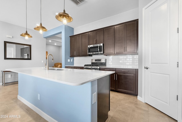 kitchen featuring a kitchen island with sink, sink, dark brown cabinetry, and appliances with stainless steel finishes