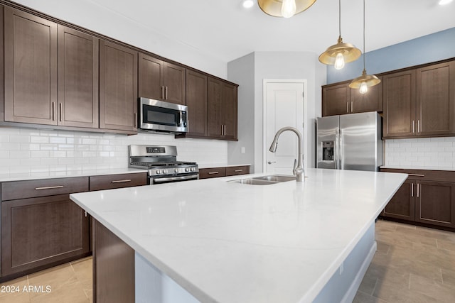 kitchen featuring tasteful backsplash, an island with sink, sink, stainless steel appliances, and dark brown cabinets