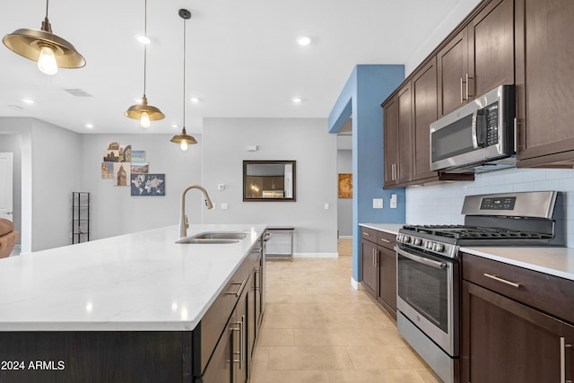 kitchen featuring sink, a kitchen island with sink, backsplash, hanging light fixtures, and stainless steel appliances