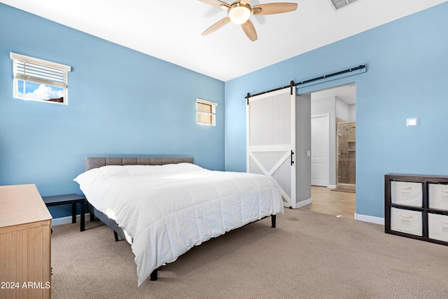 bedroom featuring ceiling fan, a barn door, light carpet, and ensuite bath