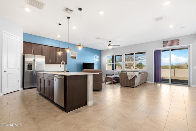 kitchen featuring pendant lighting, sink, ceiling fan, appliances with stainless steel finishes, and a kitchen island with sink