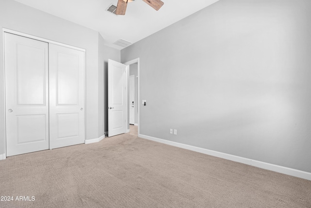 unfurnished bedroom featuring ceiling fan, light colored carpet, and a closet