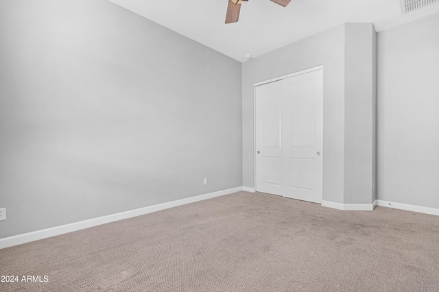 unfurnished bedroom with ceiling fan, carpet floors, and a closet