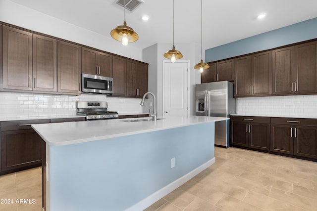 kitchen featuring dark brown cabinetry, stainless steel appliances, sink, and a center island with sink