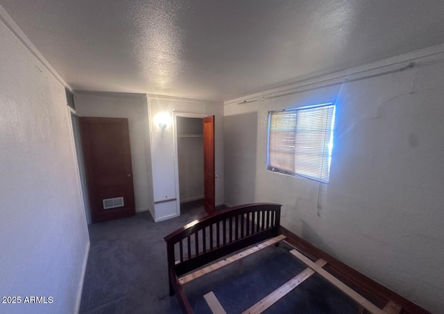 unfurnished bedroom featuring a closet, visible vents, a textured ceiling, and carpet floors