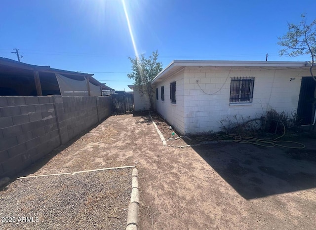 view of home's exterior with concrete block siding and fence