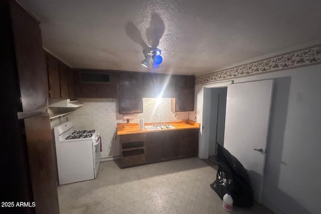 kitchen featuring a sink, white range with gas cooktop, visible vents, and dark brown cabinetry