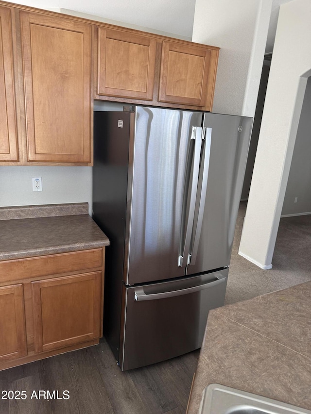 kitchen with dark wood-type flooring and stainless steel refrigerator