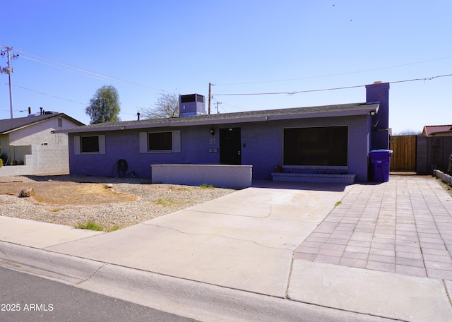 ranch-style house with stucco siding, central AC, a chimney, and fence