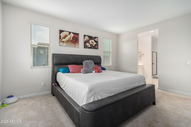 bedroom with multiple windows, connected bathroom, and light carpet