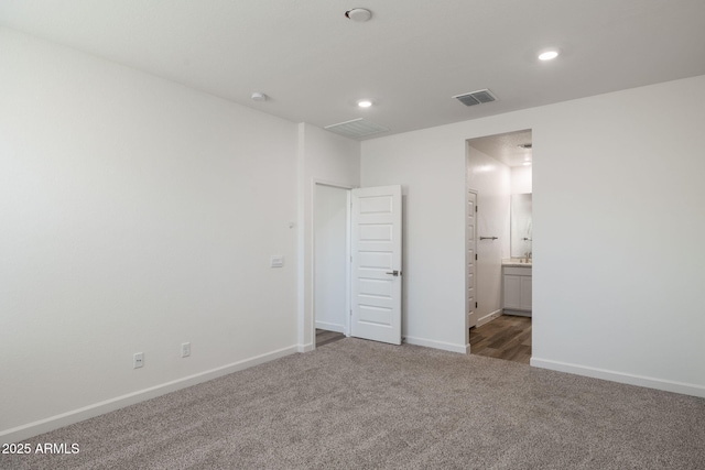 unfurnished bedroom featuring ensuite bathroom and dark carpet