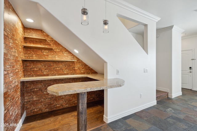 bar with ornamental molding, brick wall, and pendant lighting