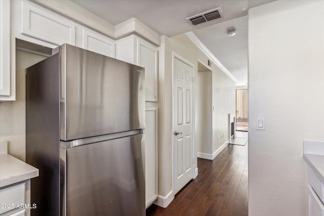 kitchen featuring stainless steel refrigerator, ornamental molding, dark hardwood / wood-style flooring, and white cabinets