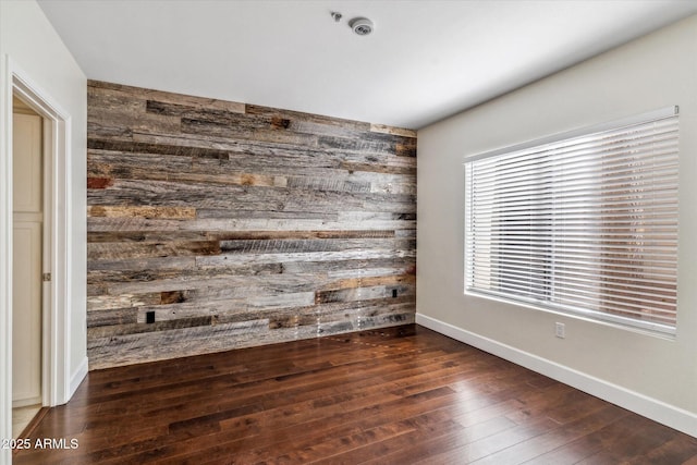 spare room with dark wood-type flooring and wooden walls