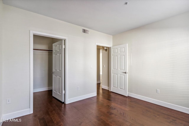 unfurnished bedroom with dark wood-type flooring and a closet