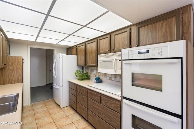 kitchen with white appliances, light tile patterned floors, and backsplash