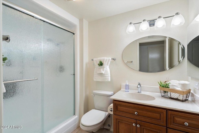 bathroom featuring a shower with door, vanity, and toilet