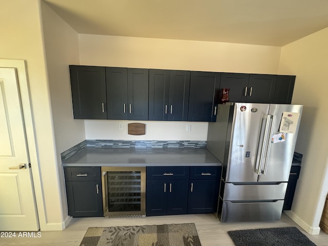 kitchen featuring beverage cooler, light hardwood / wood-style floors, and stainless steel refrigerator