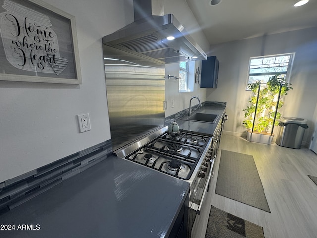 kitchen with ventilation hood, stainless steel cooktop, sink, and a wealth of natural light