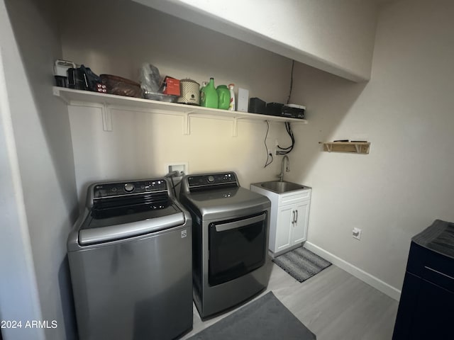 laundry area featuring light hardwood / wood-style floors, cabinets, independent washer and dryer, and sink