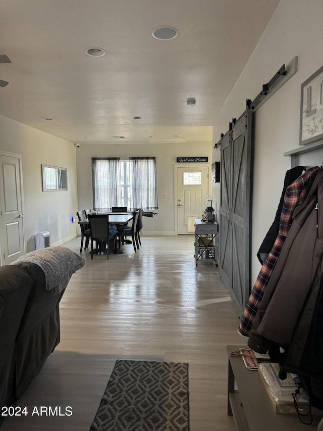 living room with a barn door and light hardwood / wood-style floors