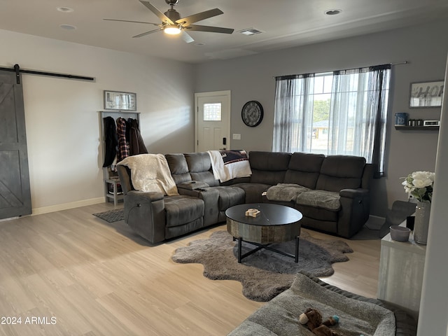 living room featuring a barn door, ceiling fan, and light wood-type flooring