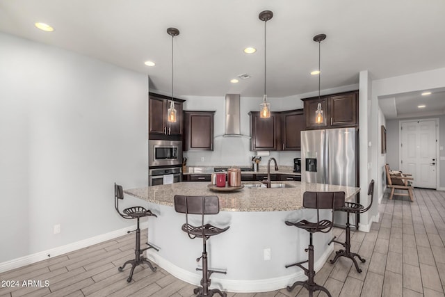 kitchen featuring sink, stainless steel appliances, wall chimney range hood, and light hardwood / wood-style floors