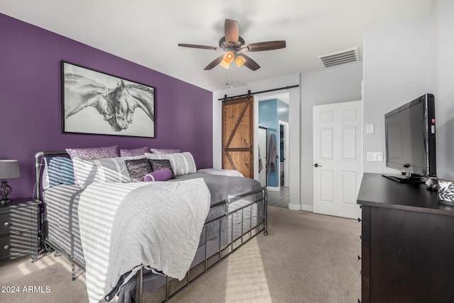 bedroom featuring ceiling fan, a barn door, and light colored carpet