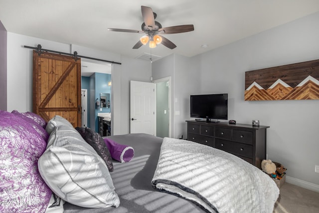 bedroom with carpet, ceiling fan, a barn door, and ensuite bath