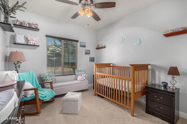 carpeted bedroom with ceiling fan and a nursery area