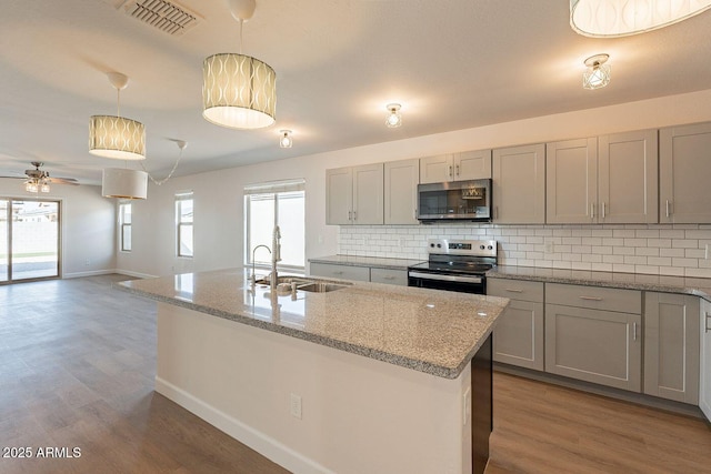 kitchen featuring wood finished floors, visible vents, a sink, appliances with stainless steel finishes, and tasteful backsplash