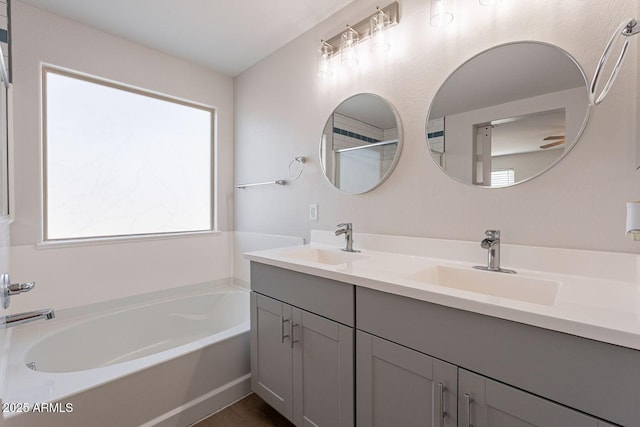 full bathroom featuring a garden tub, double vanity, and a sink