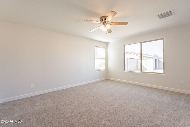 empty room featuring visible vents, light colored carpet, baseboards, and ceiling fan