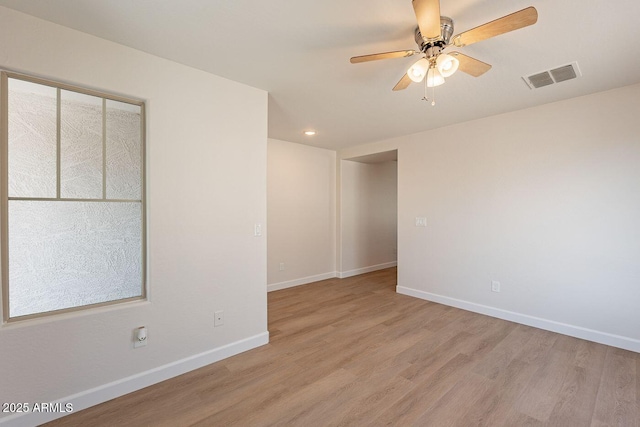 empty room with visible vents, ceiling fan, light wood-type flooring, and baseboards