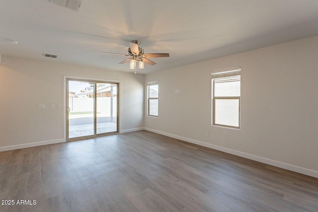 spare room featuring visible vents, a ceiling fan, baseboards, and wood finished floors